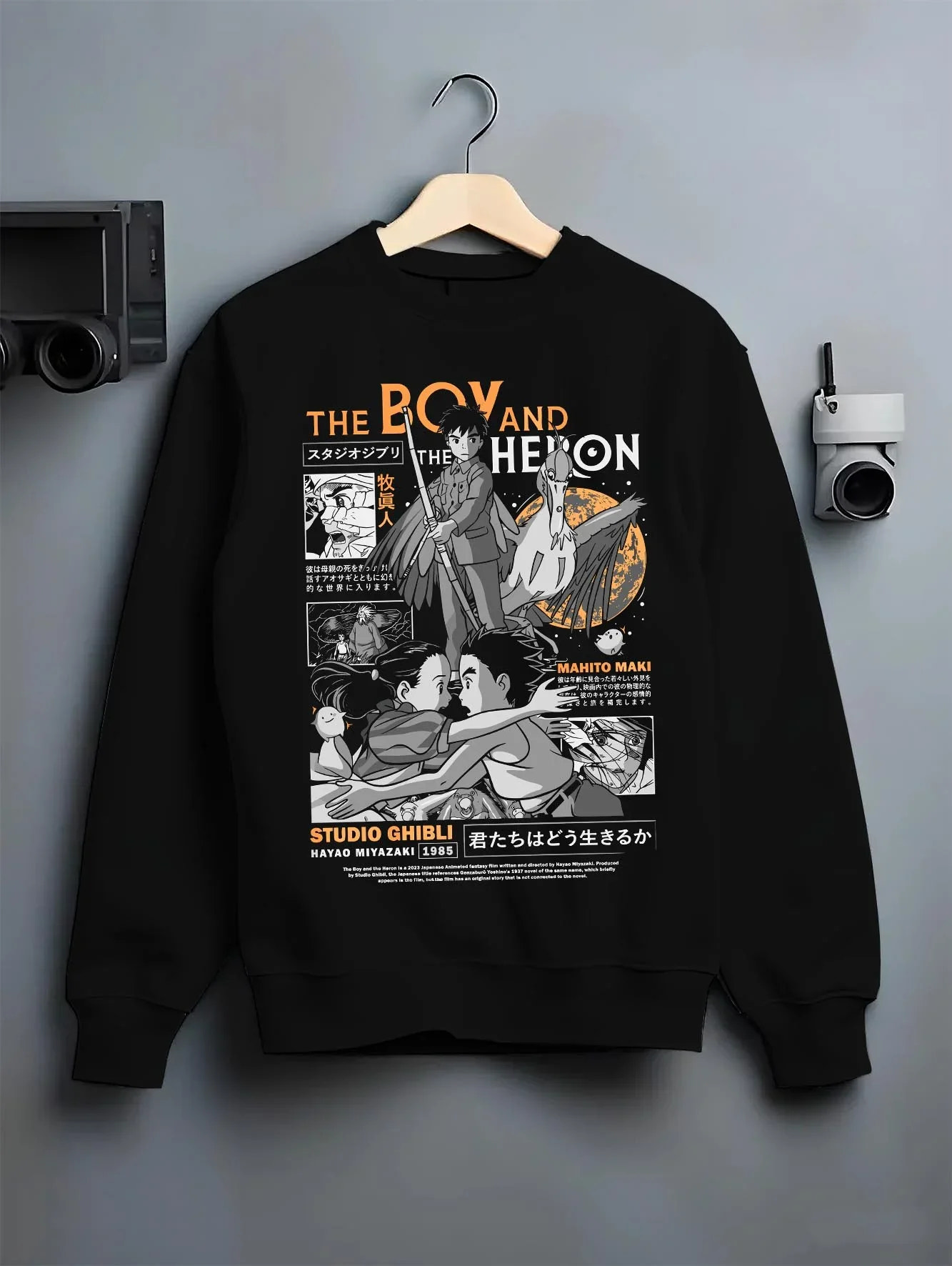 Black crewneck sweatshirt on hanger with The Boy And The Heron Hoodie Studio Ghibli Cover graphic nan anime design.