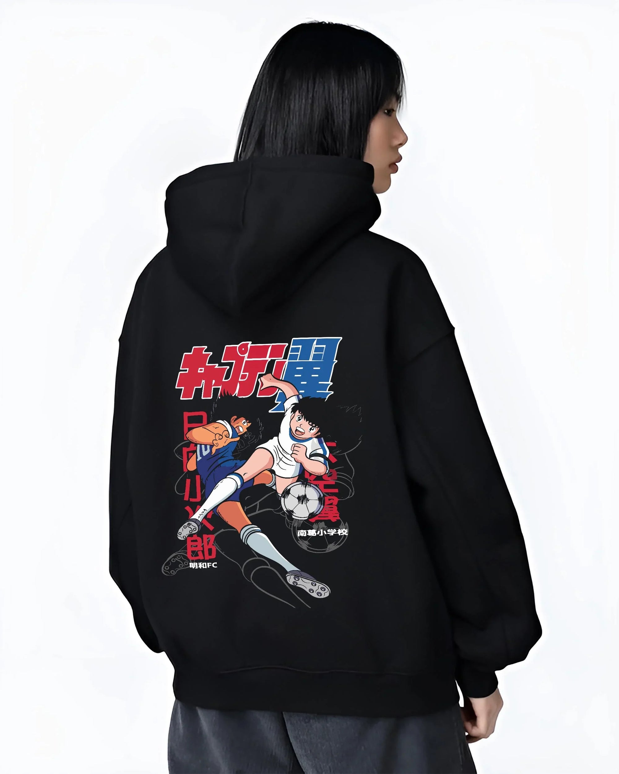 Black hoodie worn by female model, back view with Tsubasa Duo Hoodie Captain Tsubasa Soccer Team Play graphic bold anime graphic.