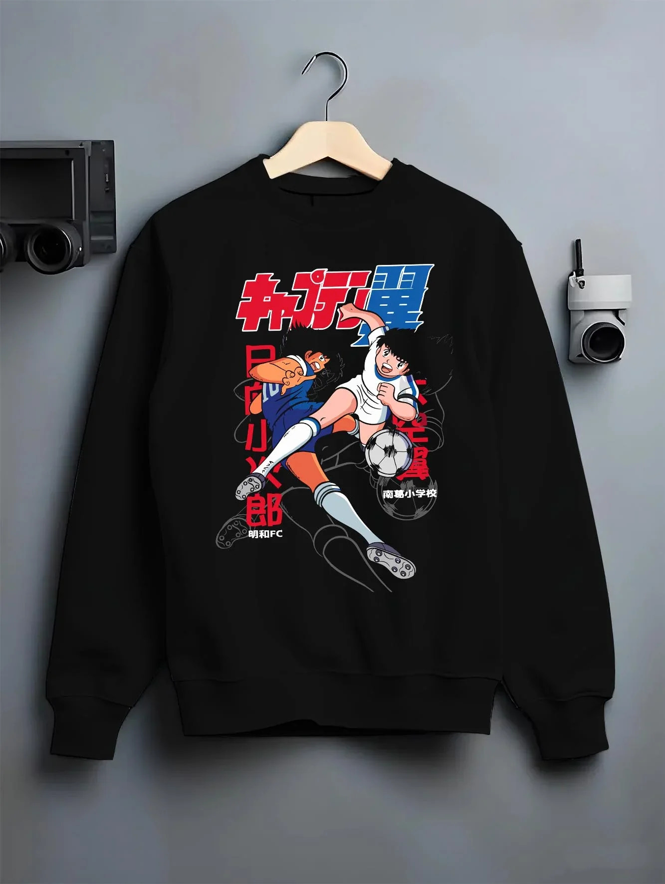 Black crewneck sweatshirt on hanger with Tsubasa Duo Hoodie Captain Tsubasa Soccer Team Play graphic bold anime graphic.