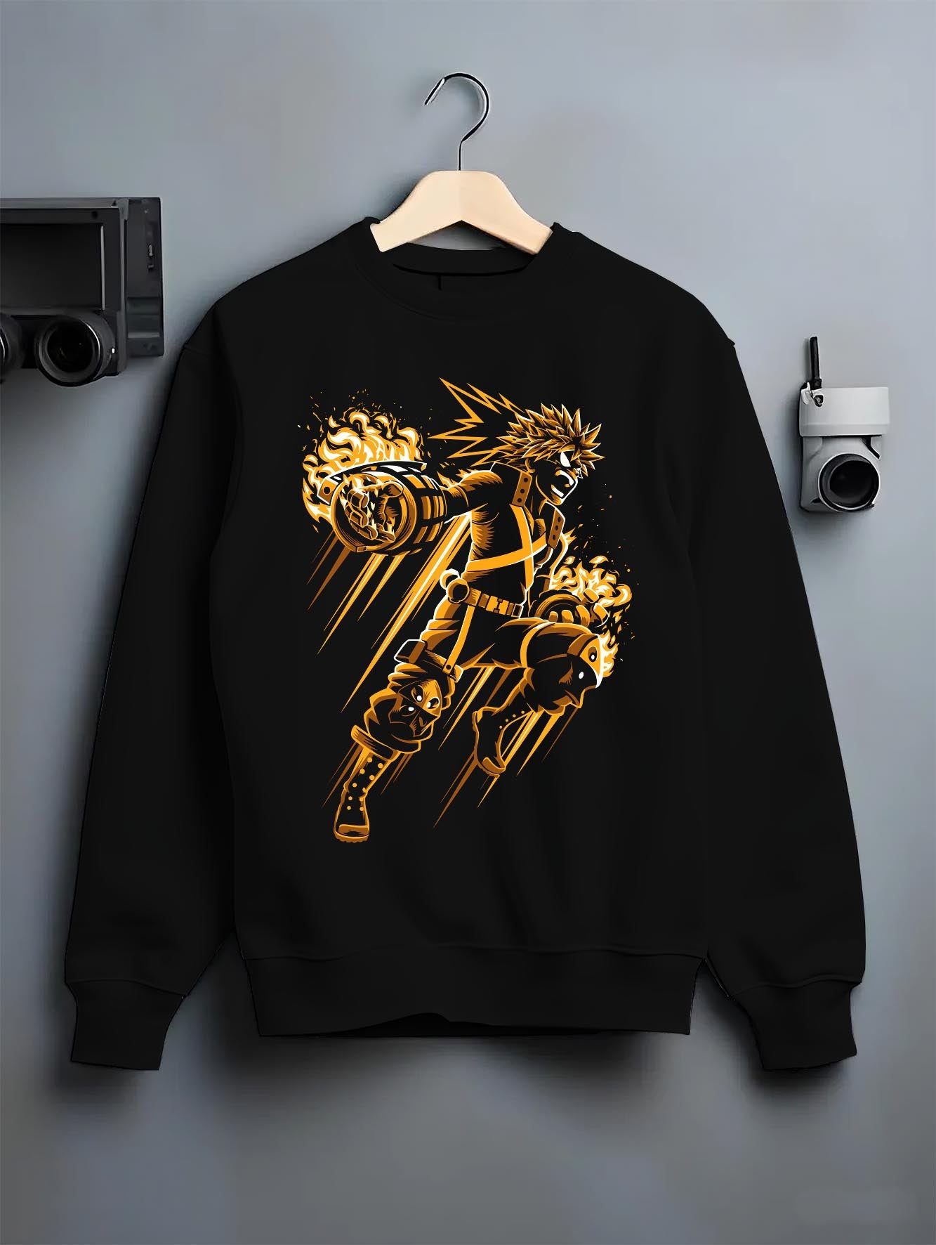 Black crewneck sweatshirt on hanger against grey wall, Bakugo shonen battle back graphic with blasting gauntlets and fiery accents.