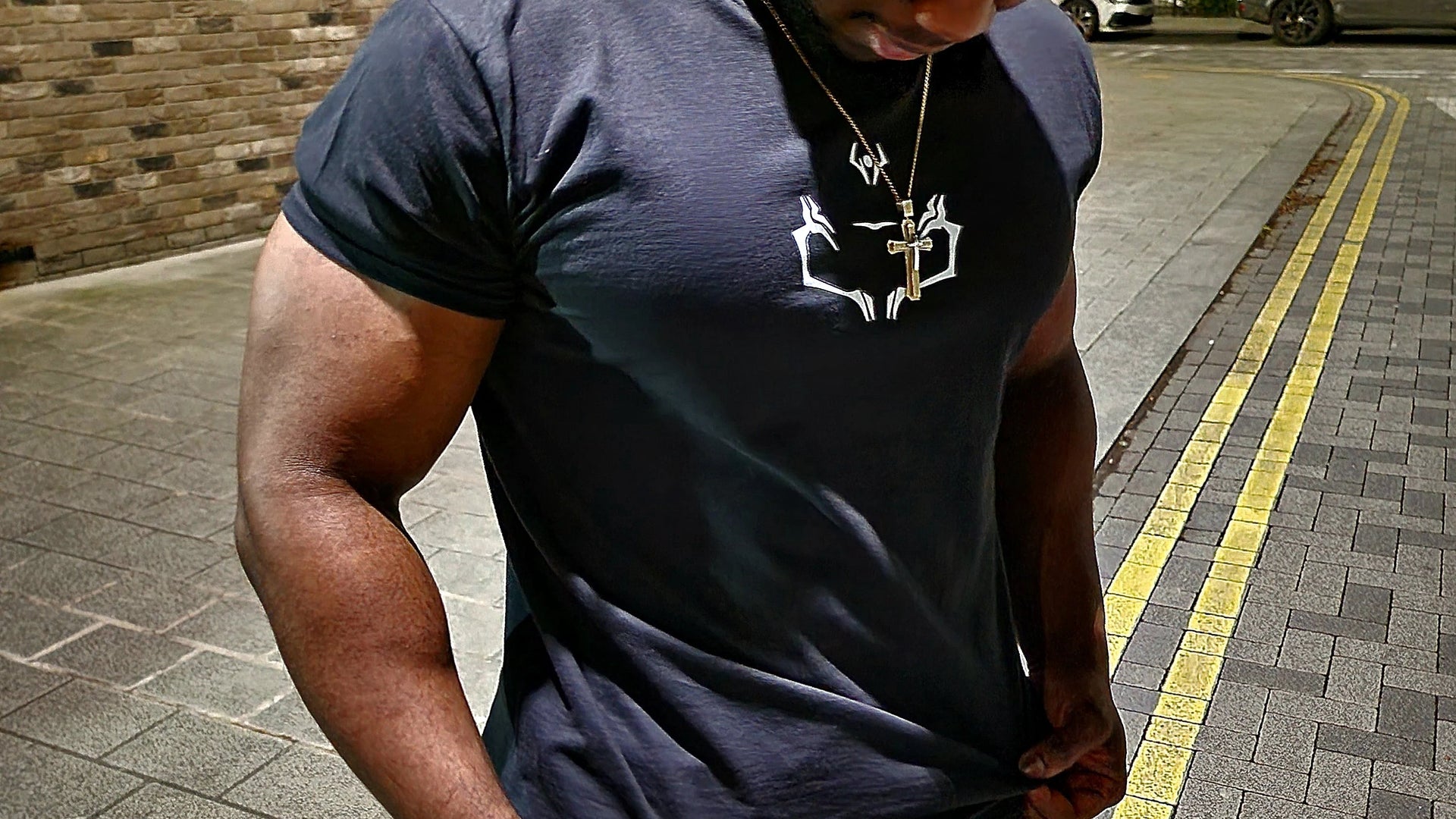 Male model wearing black Kunai anime T-shirt with Sukuna curse symbol design, Japanese-inspired streetwear photographed in urban night setting for manga fans.
