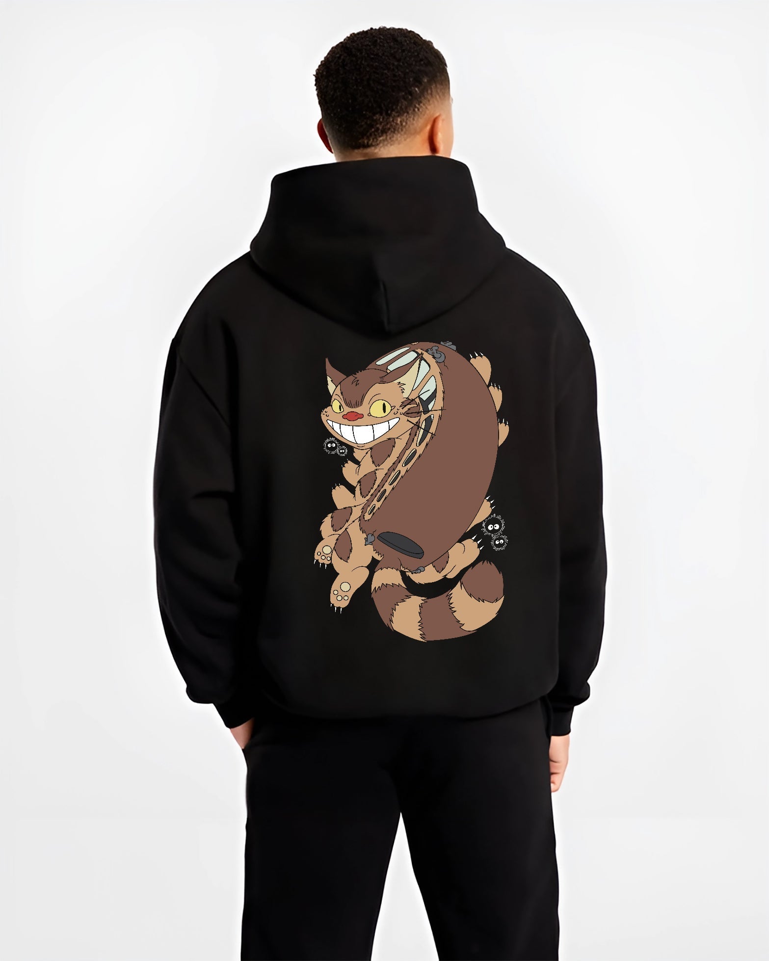Black hoodie worn by a male model, back view, featuring Totoro Catbus with soot sprites; nostalgic 90s graphic and urban fashion flair.
