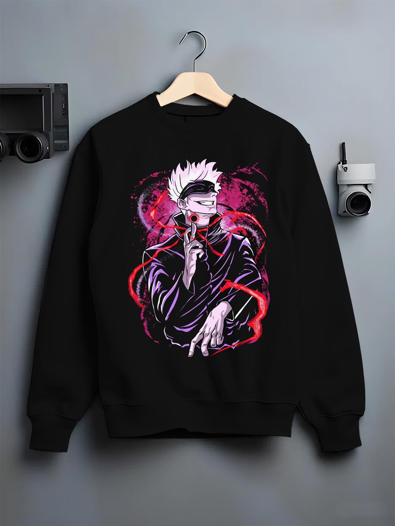 Black crewneck sweatshirt on hanger against grey wall, featuring Gojo Satoru anime poster style print with red energy and magenta aura.
